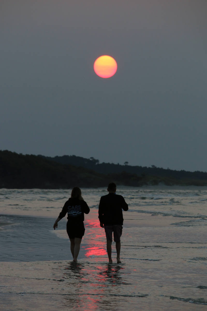 A couple walks along the beach in Cherry Grove, S.C., early Thursday, July 22, 2021. Smoke from ...