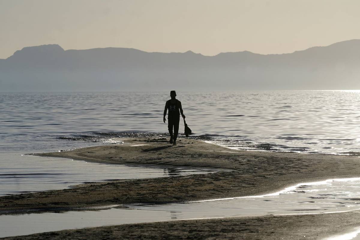 A man walks along a sand bar at the receding edge of the Great Salt Lake on June 13, 2021, near ...