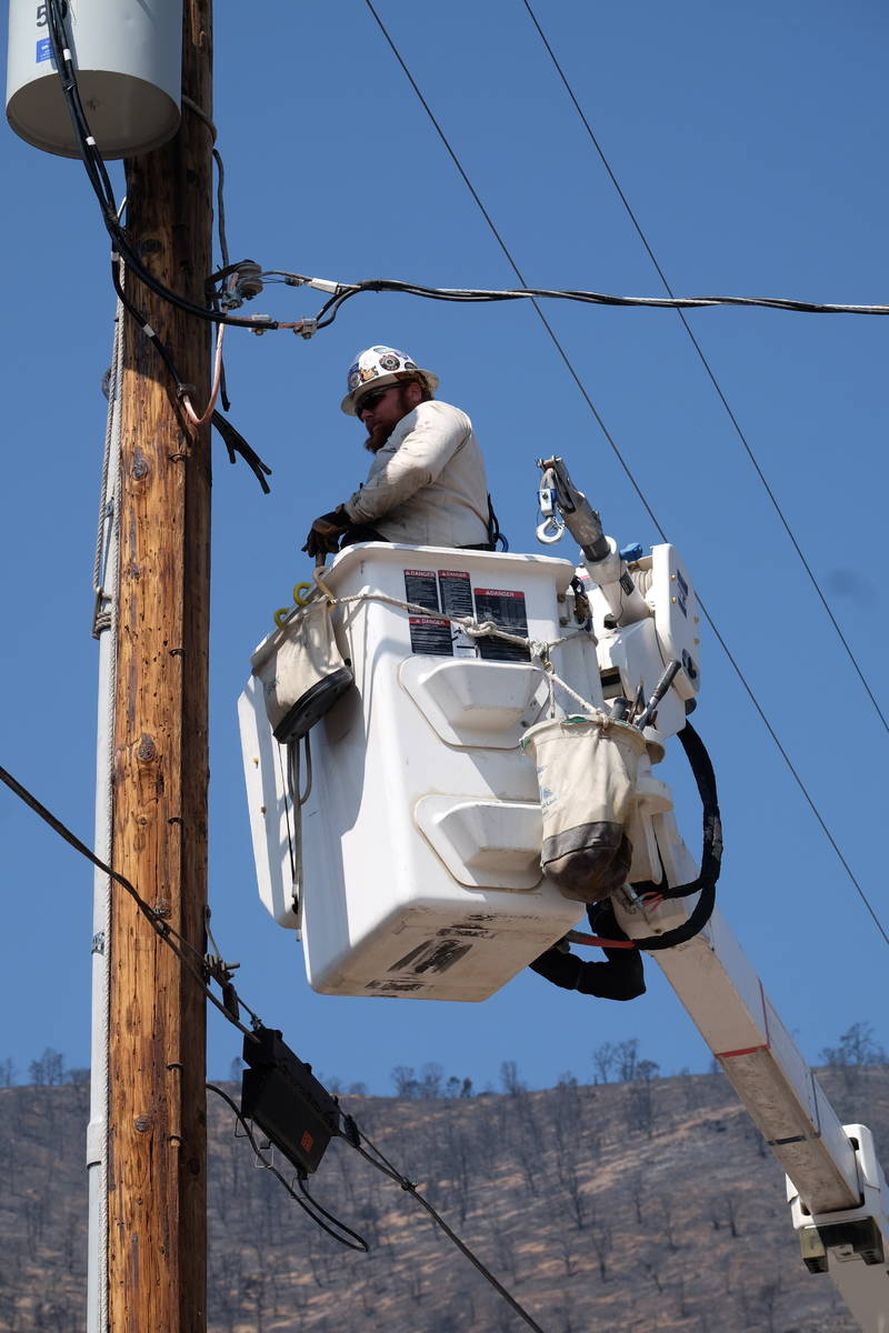 A utility worker repairs power lines at a burned-our subdivision partially destroyed by the Tam ...