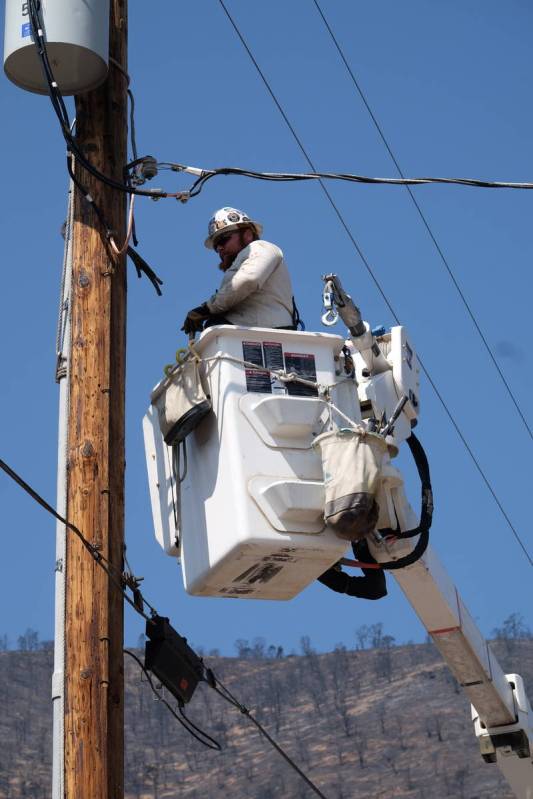 A utility worker repairs power lines at a burned-our subdivision partially destroyed by the Tam ...