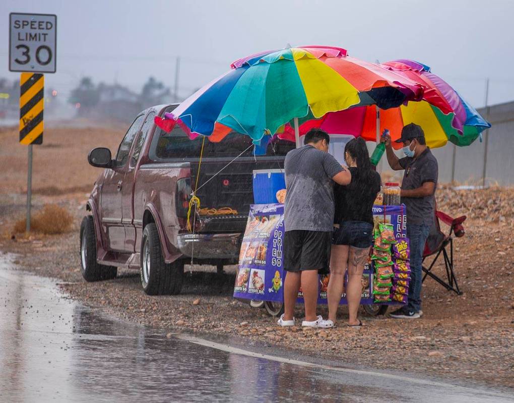 People stop for a bite to eat under some umbrellas of a cart vendor along West Twain Avenue as ...