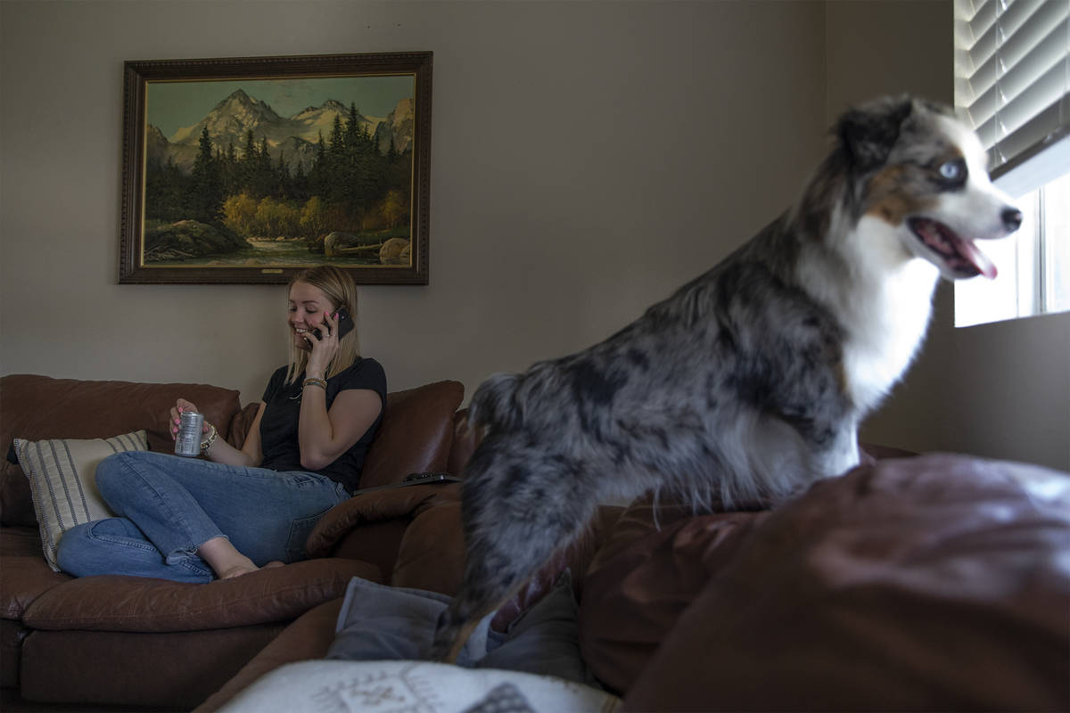 Kylee Tobler speaks with her mom on the phone while her dog, Benny, looks out the living room w ...