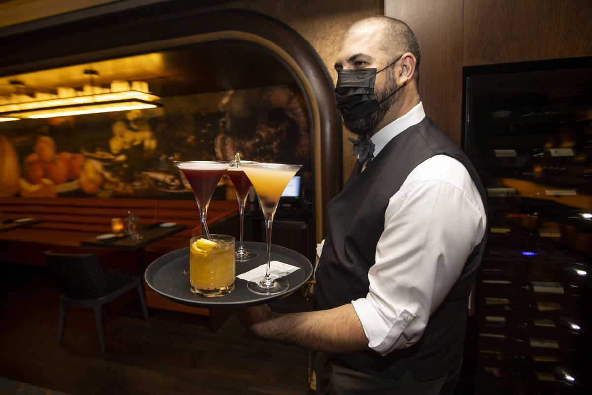 Server Aldo Alonzo delivers drinks to diners at Olives restaurant inside of Virgin Hotels Las V ...