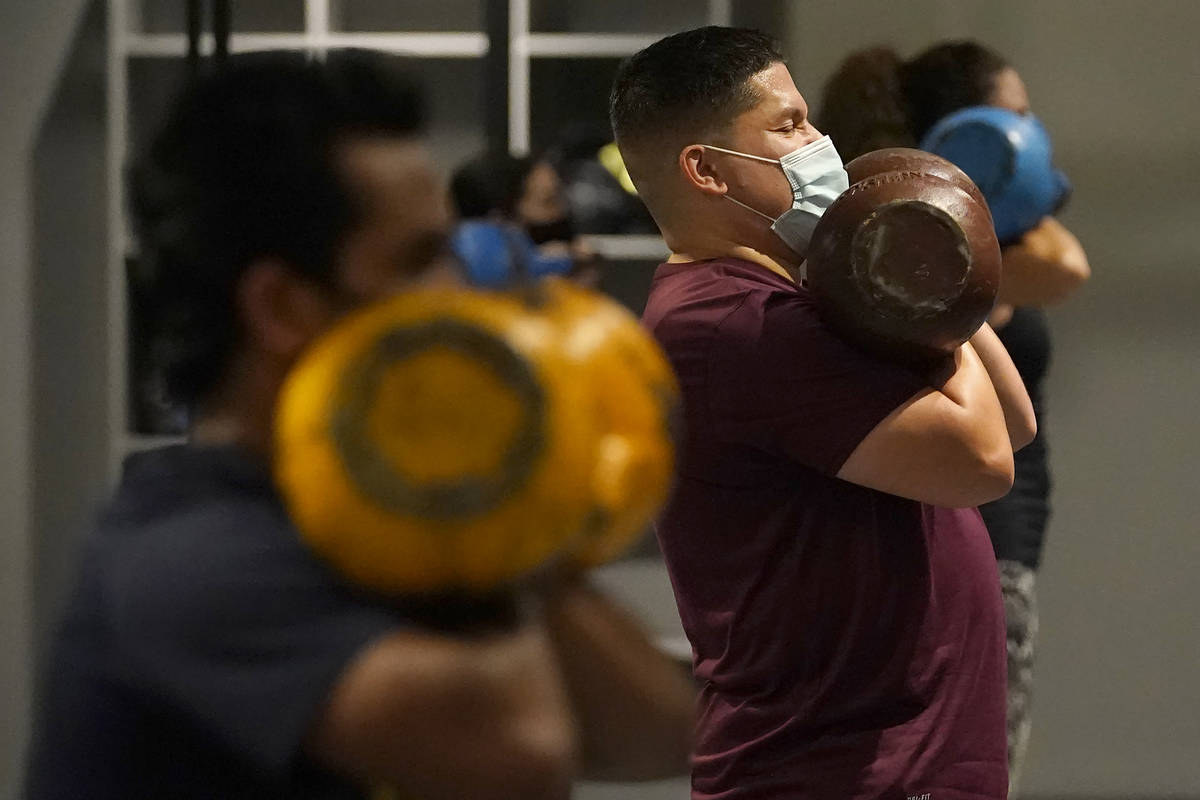 In this Nov. 24, 2020, file photo, Juan Avellan, center, and others wear masks while working ou ...