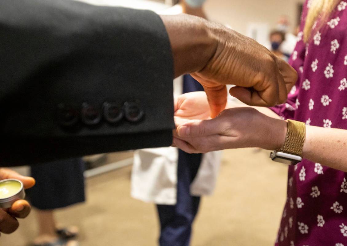 Father Don Ajoko, Phd. anoints the hands of healthcare workers and members of the nearly three ...