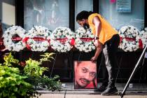 Dion Green places a portrait of his father, Derrick Fudge, of Springfield, Ohio, on Fifth Stree ...