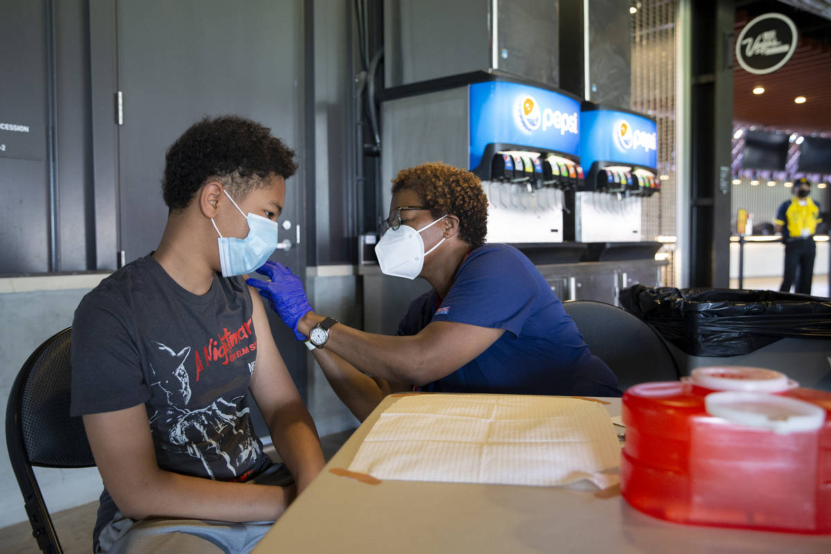 Joel Ferrell, 13, receives his first dose of the Pfizer COVID-19 vaccination from nurse Essie W ...