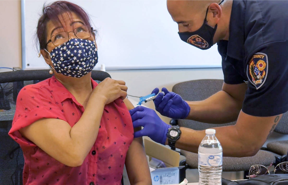 Grace Freckman receives a COVID-19 vaccine from Clark County Fire Department engineer and param ...