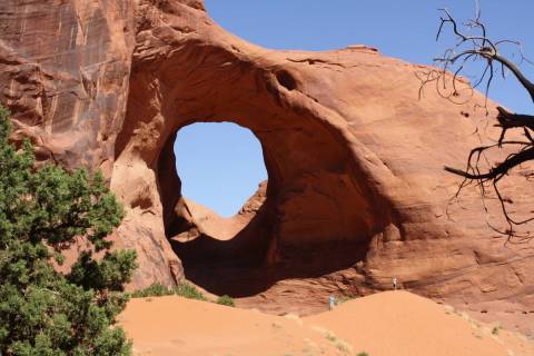Visitors climb up the sandy bank to get a closer look at the Ear of the Wind Arch. (Deborah Wall)