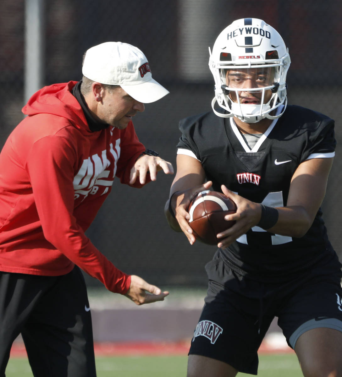 Glenn Thomas, offensive coordinator and quarterbacks coach, left, speaks to UNLV Rebels quarter ...