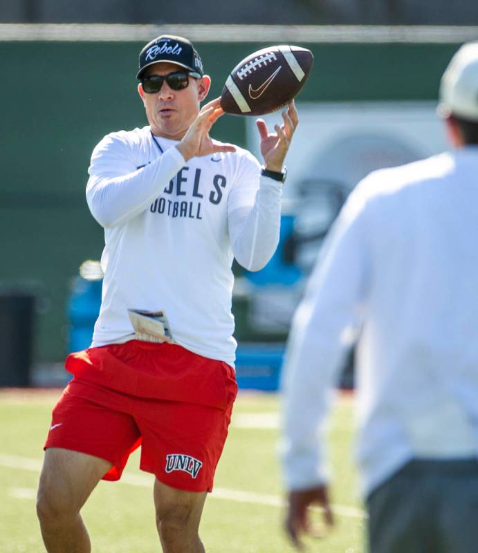 UNLV Head Coach Marcus Arroyo catches a pass from a quarterback during a drill in football team ...