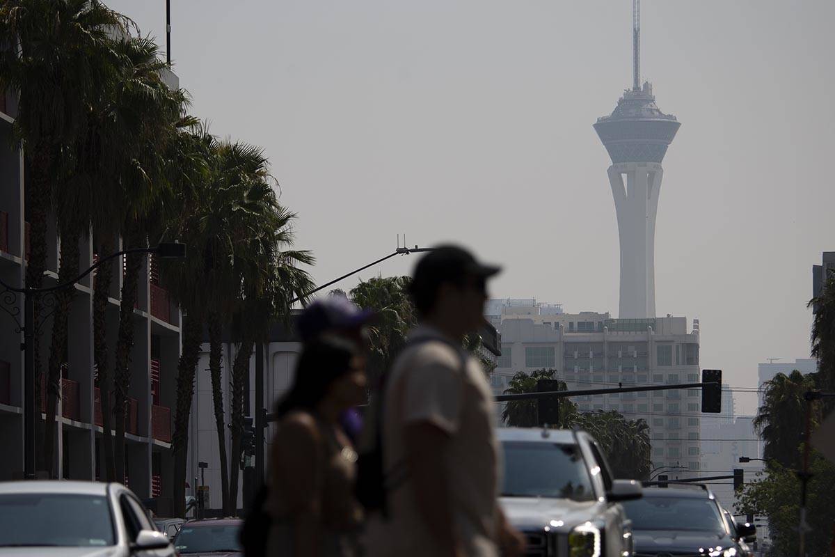 Pedestrians walk through Fremont Street Experience while smoky skies cloud the STRAT on Saturda ...