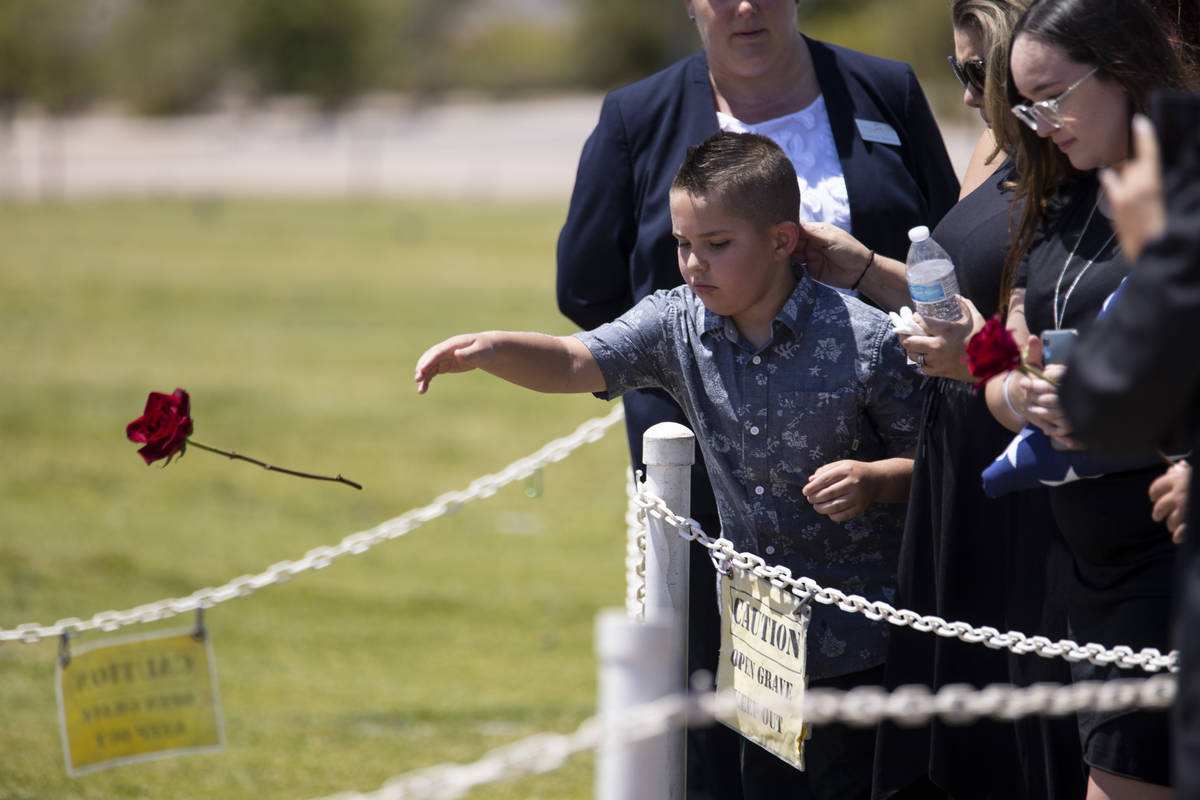 In this July 8, 2021, file photo, Noah Swanger, 8, tosses a rose on the gravesite of his father ...