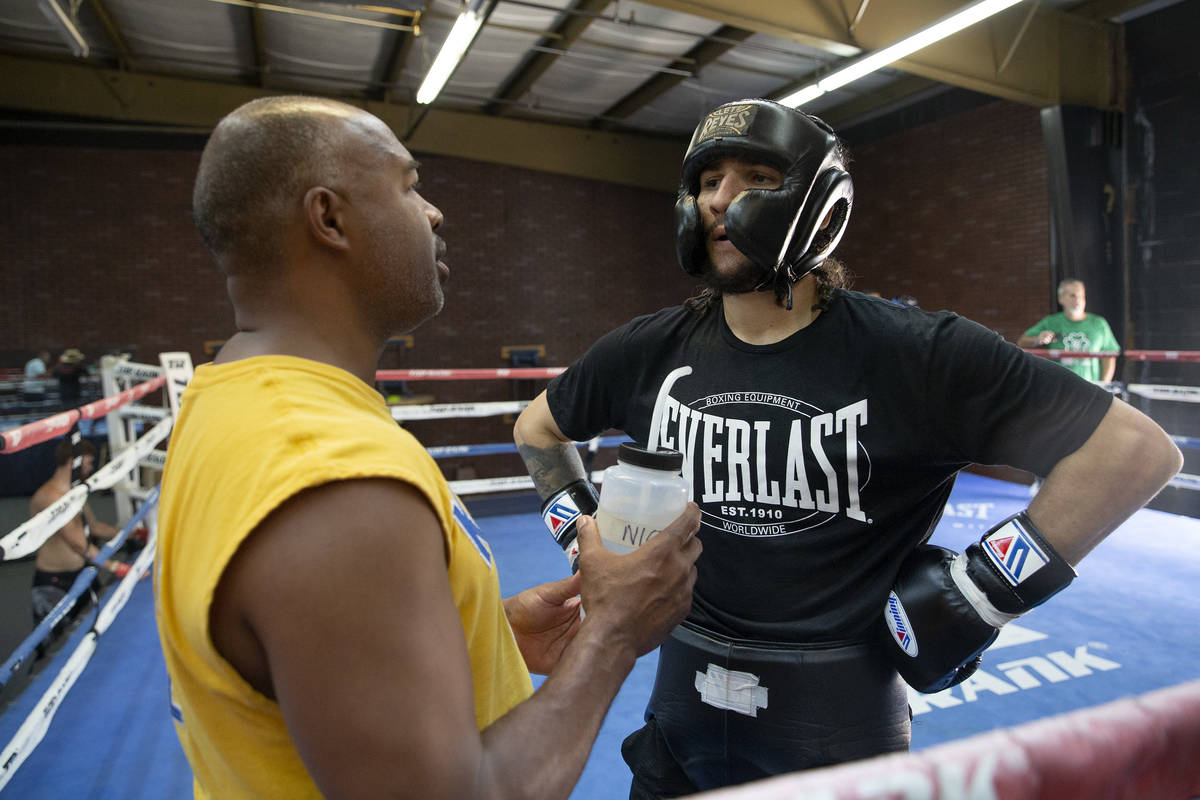 Boxing trainer SugarHill communicates with Nico Ali Walsh on the sidelines during training at T ...