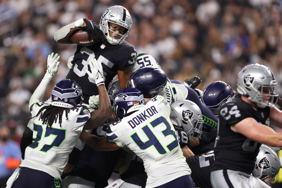 Las Vegas Raiders running back B.J. Emmons (35) leaps over Seattle Seahawks safety Joshua Moon ...