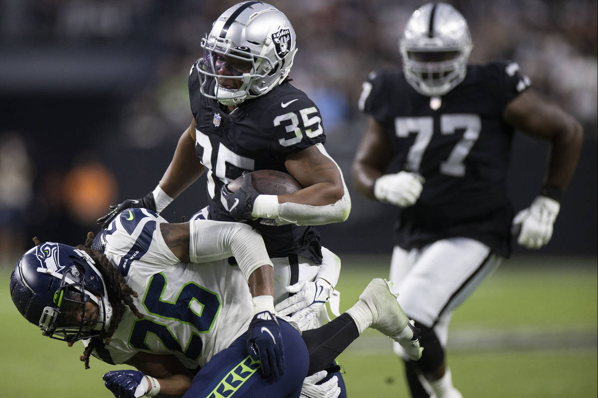 Raiders running back BJ Emmons (35) runs past Seattle Seahawks defensive back Ryan Neal (26) in ...