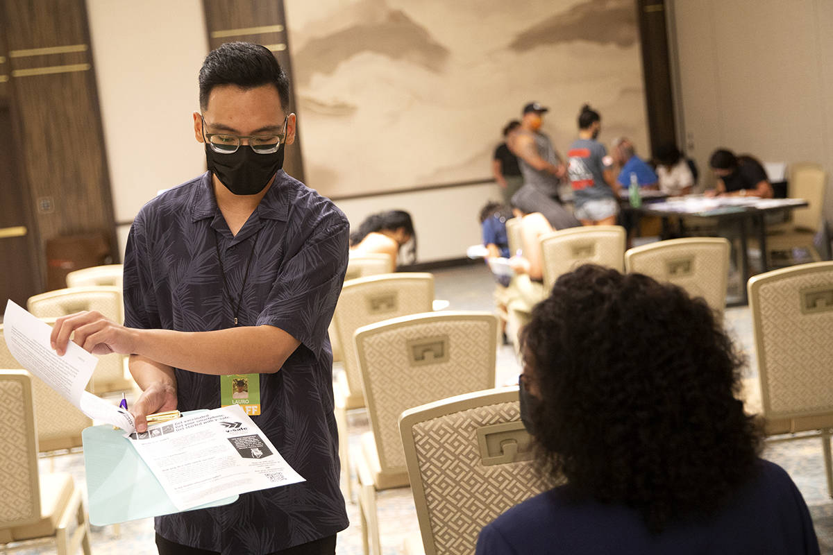 Lauro Solomo, community health worker with Immunize Nevada, shares paperwork with Jessica Dula, ...