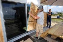 James Masog, center, and Gary Tavares, right, move particle board into place to board up the sl ...