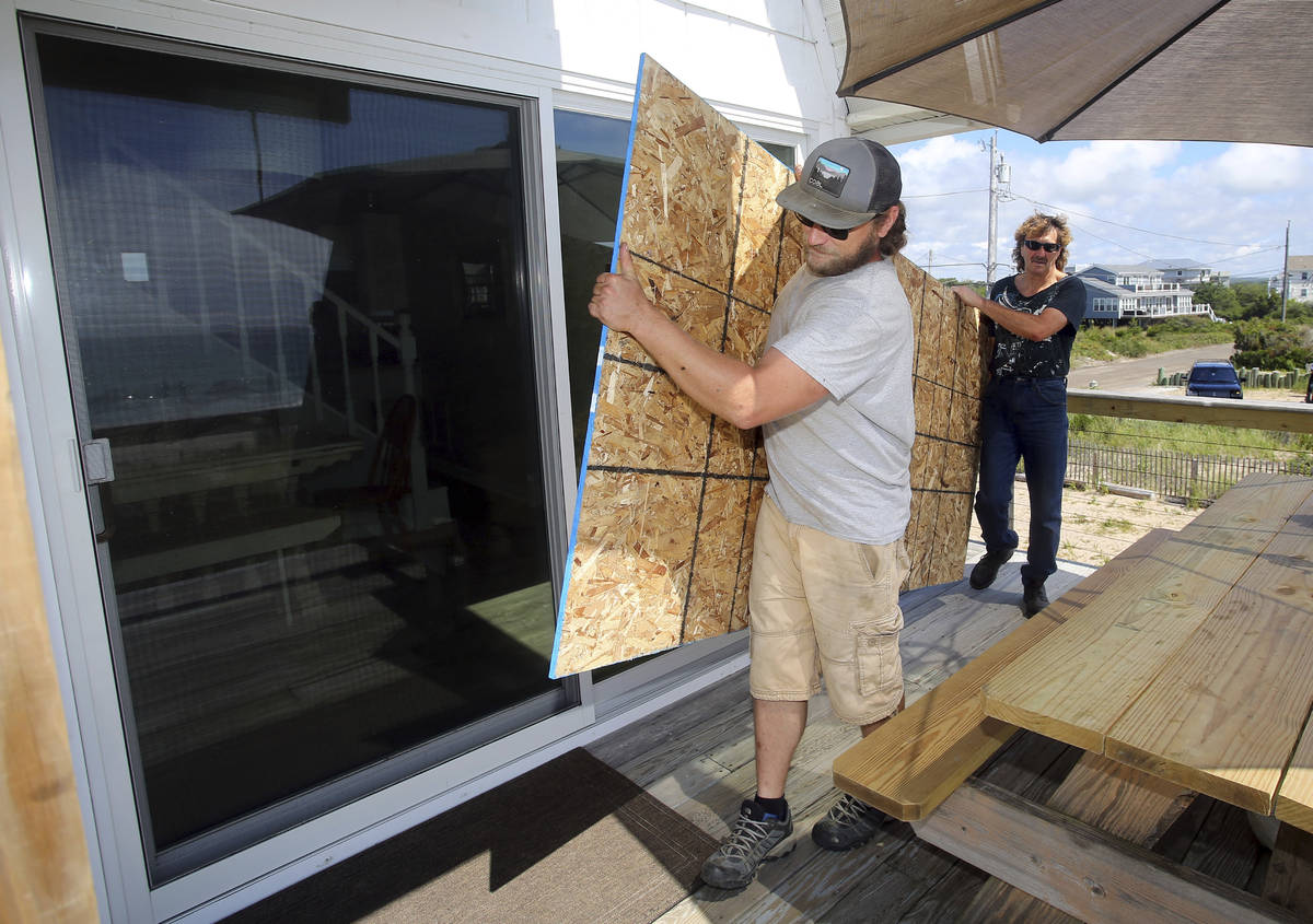 James Masog, center, and Gary Tavares, right, move particle board into place to board up the sl ...