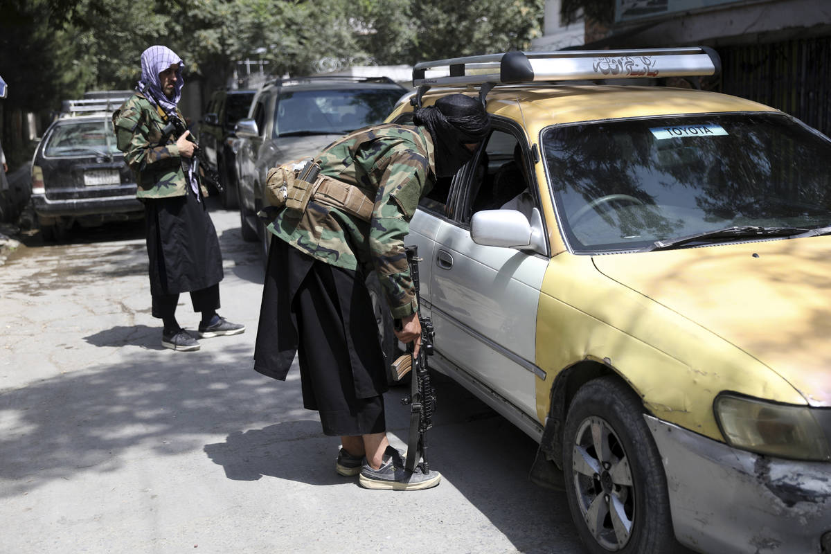 Taliban fighters search a vehicle at a checkpoint on the road in the Wazir Akbar Khan neighborh ...