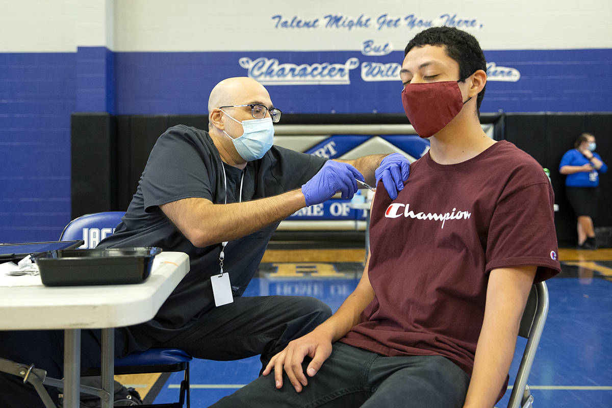 Nurse Christian Hyderkhan administers the Pfizer COVID-19 vaccine to high school senior Edwin G ...