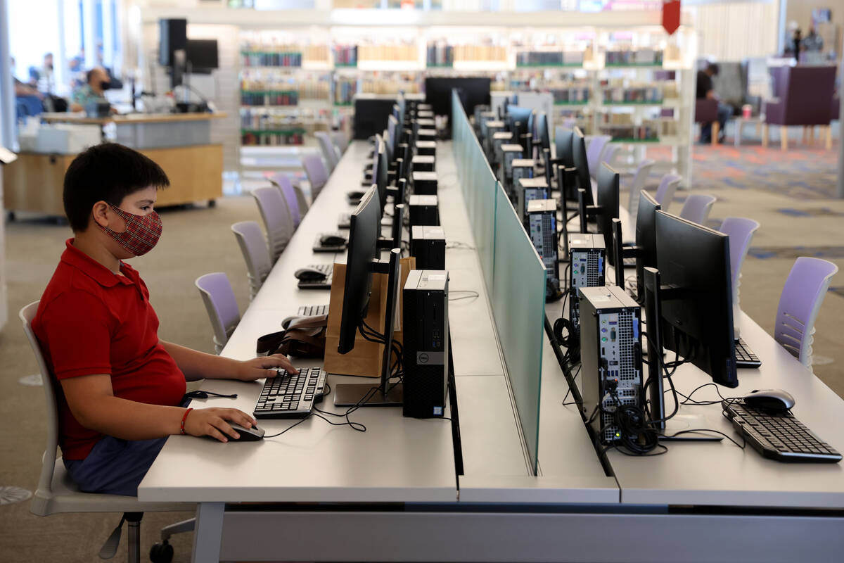 Christian Perez, 11, uses a computer while his mother takes an English-as-a-second-language cla ...