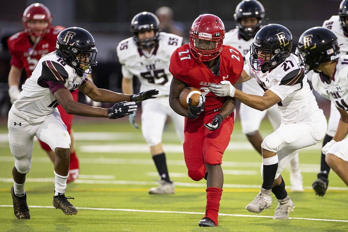 Arbor Views (27) runs the ball under pressure from Faith Lutheran's Vicentico Pringle (27) and ...