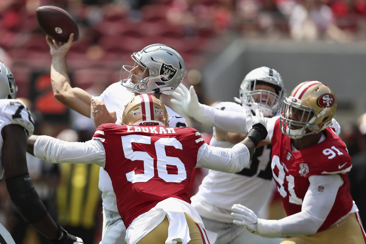Las Vegas Raiders quarterback Nathan Peterman, top, passes while pressured by San Francisco 49e ...