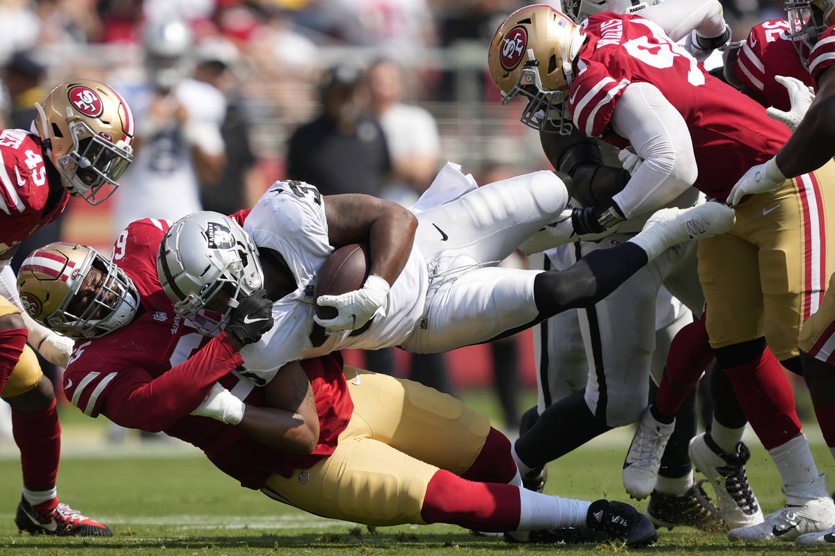 Las Vegas Raiders' B.J. Emmons, middle, is tackled by San Francisco 49ers defensive linemen Dar ...