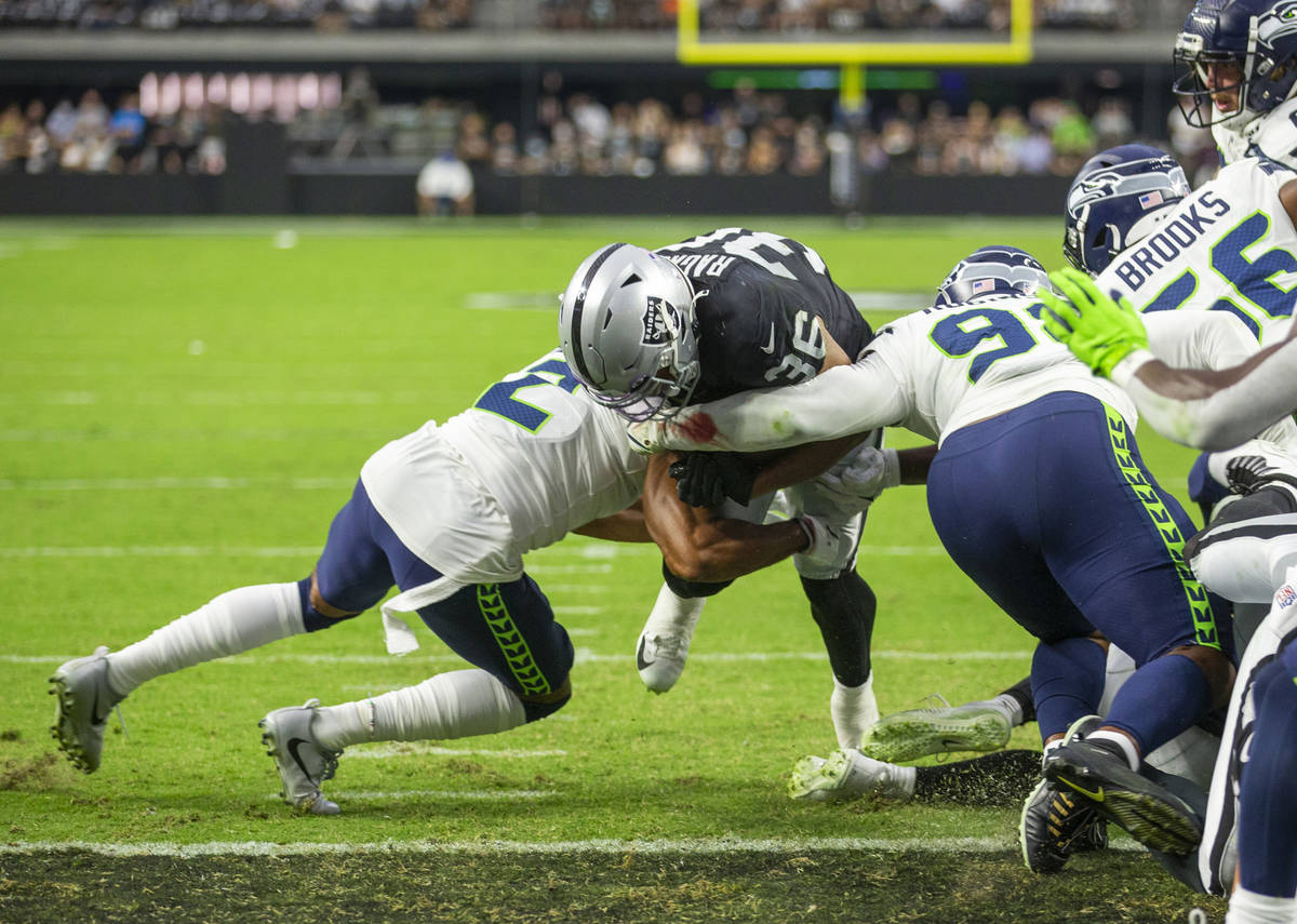 Raiders running back Trey Ragas (36) lowers his helmet to split the defense of Seattle Seahawks ...