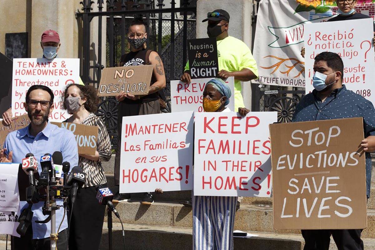 People from a coalition of housing justice groups hold signs protesting evictions during a news ...