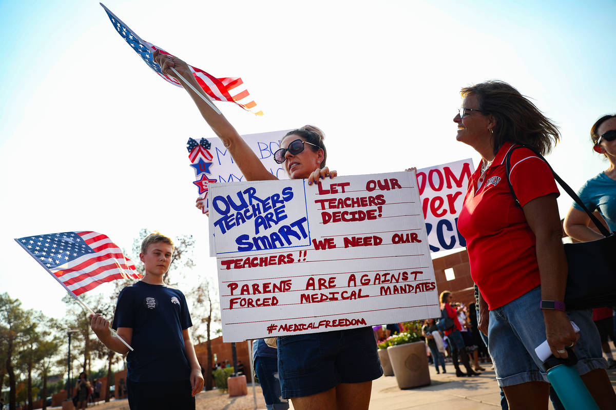 Elizabeth Hammack, a mother with children in the district, center, holds a sign advocating that ...