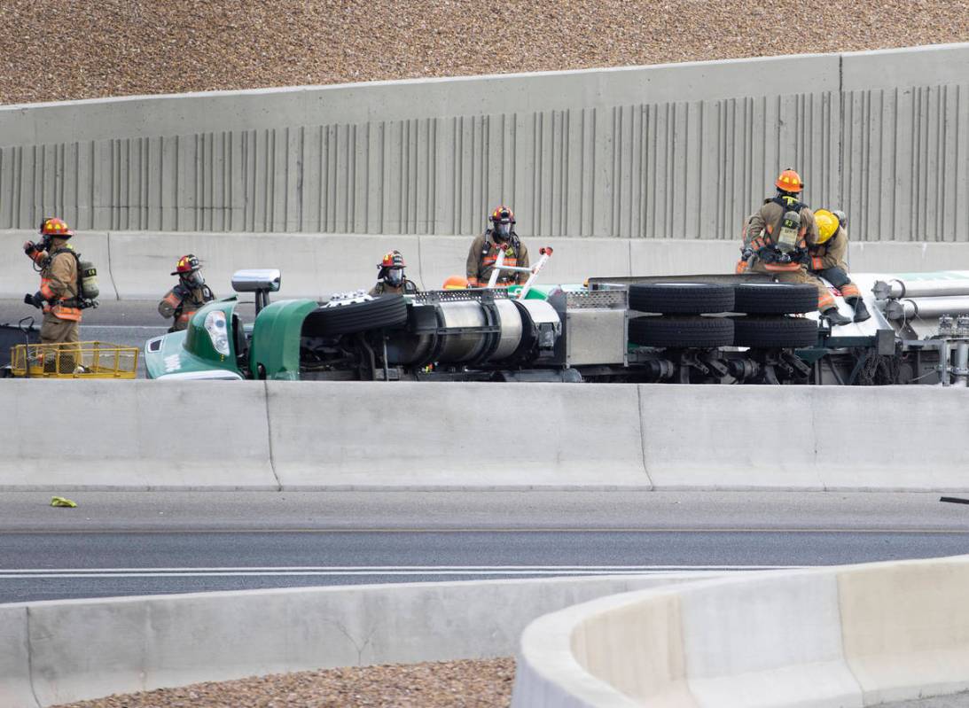 Emergency personnel work at the scene where a fuel tanker truck overturned on U.S. Highway 95 o ...