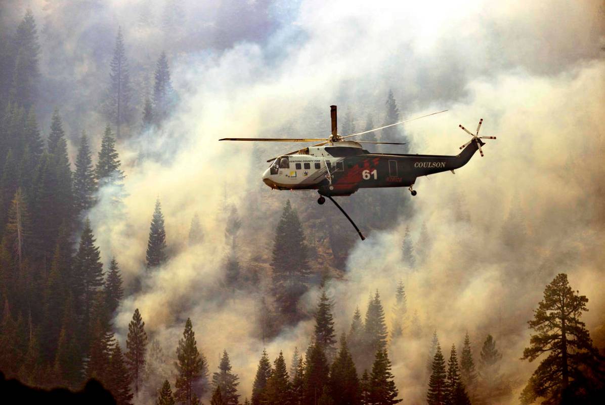 A helicopter from the Ventura County Fire department returns for more water to drop on a ridge ...