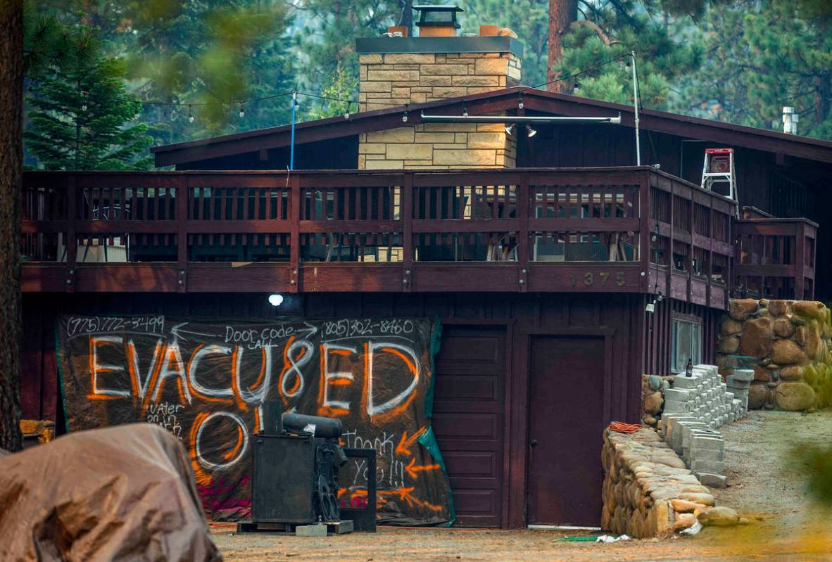 A sign is hung on the garage of an evacuated home from the Caldor Fire in Tahoe Meadows on Wedn ...