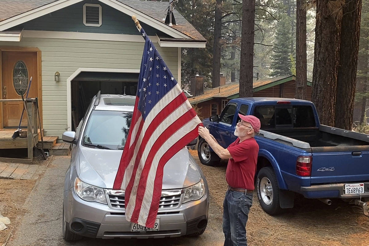 Bill Roberts rolls up an American flag in front of his house in South Lake Tahoe, Calif., on Tu ...