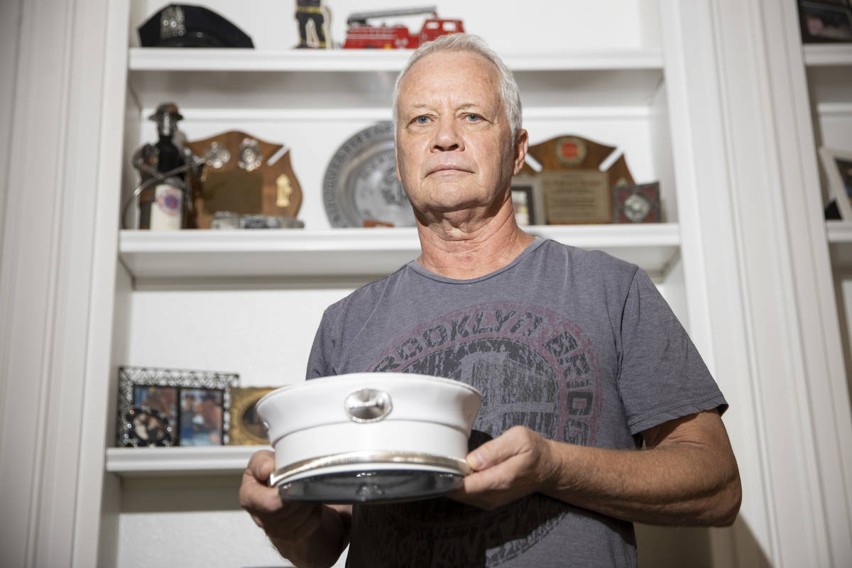 Ed Bergen, a retired New York City firefighter, poses for a portrait while holding his fire dep ...
