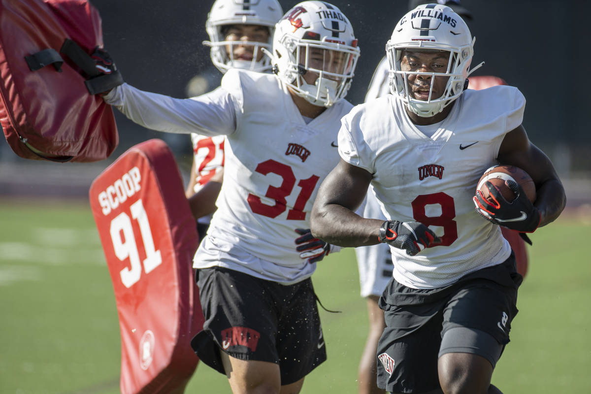 UNLV running back Charles Williams (8) runs past teammate Josh Tihada (31) after hitting a pad ...