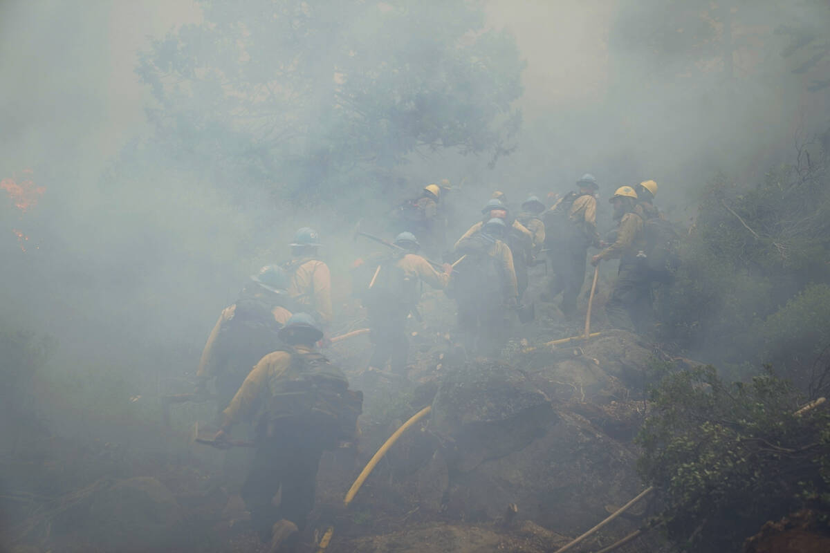 Members of a hotshot crew walk through thick smoke from the Caldor Fire in South Lake Tahoe, Ca ...