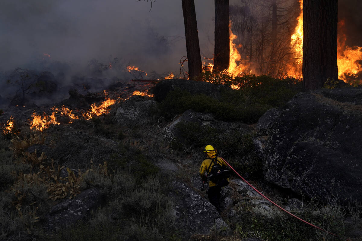 FILE - In this Sept. 2, 2021, file photo, a firefighter carries a water hose toward a spot fire ...