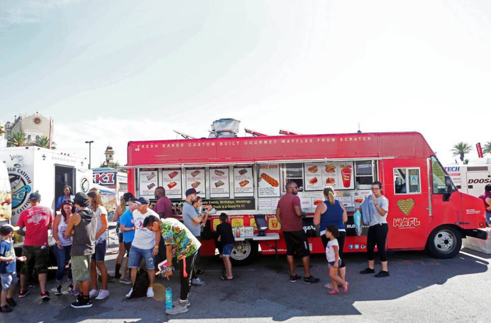 Individuals wait to receive their waffles from WAFL Truck during the Great American Foodie Fest ...