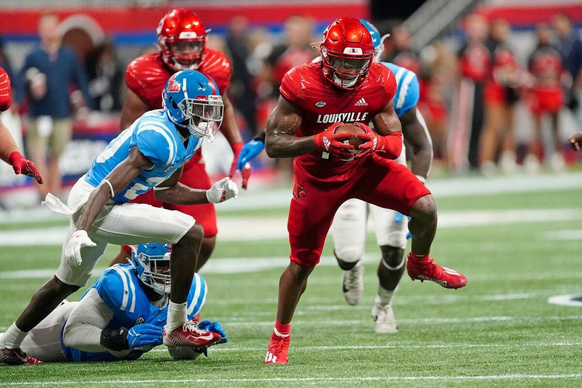 Louisville running back Jalen Mitchell (15) runs past Mississippi defensive back Keidron Smith ...