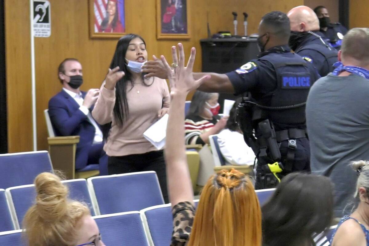 Security personnel approach a woman during Thursday's Clark County School Board meeting. (James ...