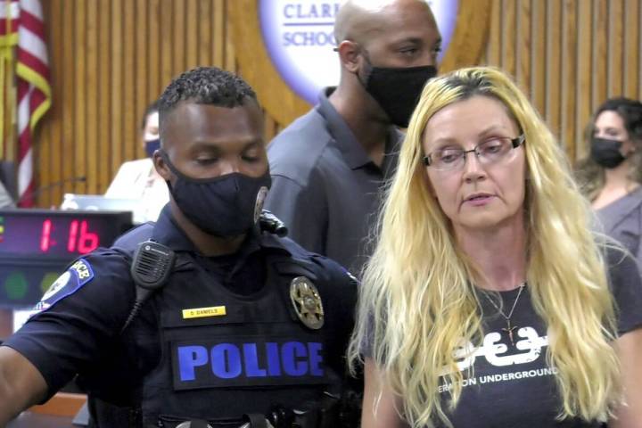 Security personnel escort a woman out of the room during Thursday's Clark County School Board m ...