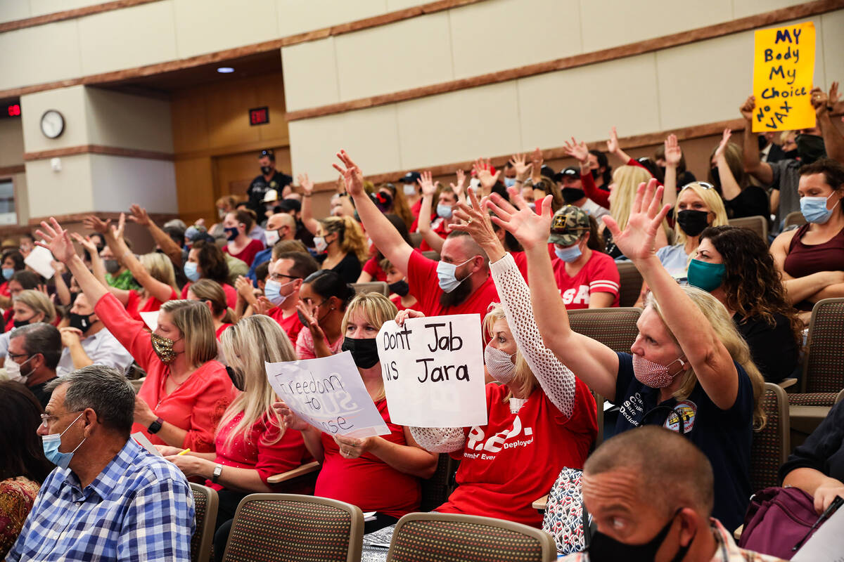 Concerned members of the public raise their hands in approval of a person’s public comme ...