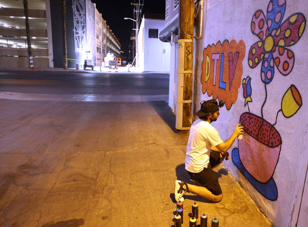 An artist who goes by the name "Pretty Done" works on his mural titled "Pretty Funk Alley" for ...