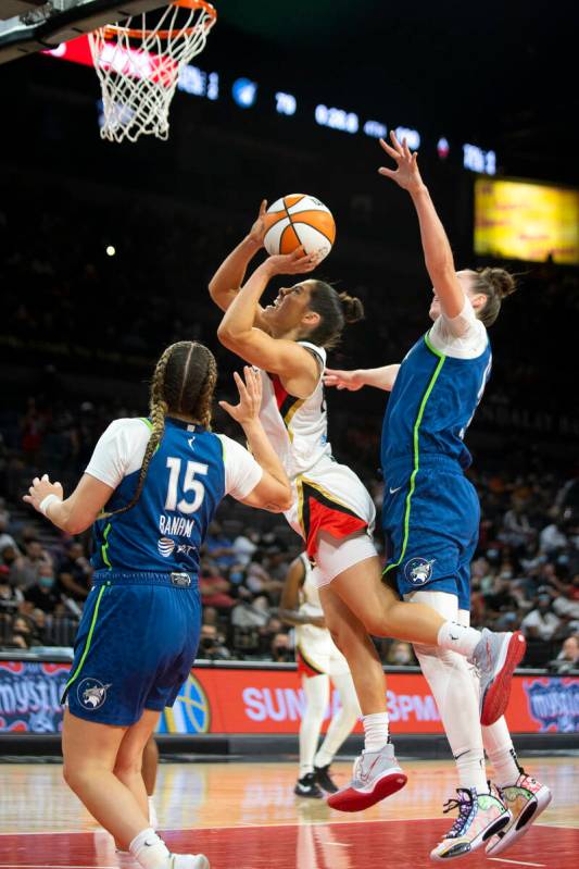 Las Vegas Aces guard Kelsey Plum (10) jumps for a layup flanked by Minnesota Lynx guard Rachel ...