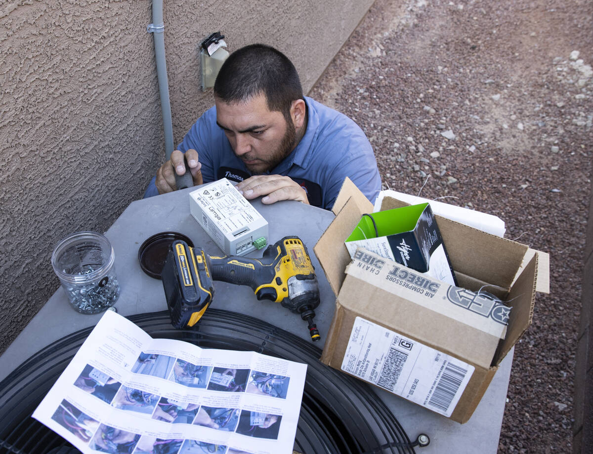 Windy City Air's technician Thomas Padron installs a soft starter as he repairs an air conditio ...