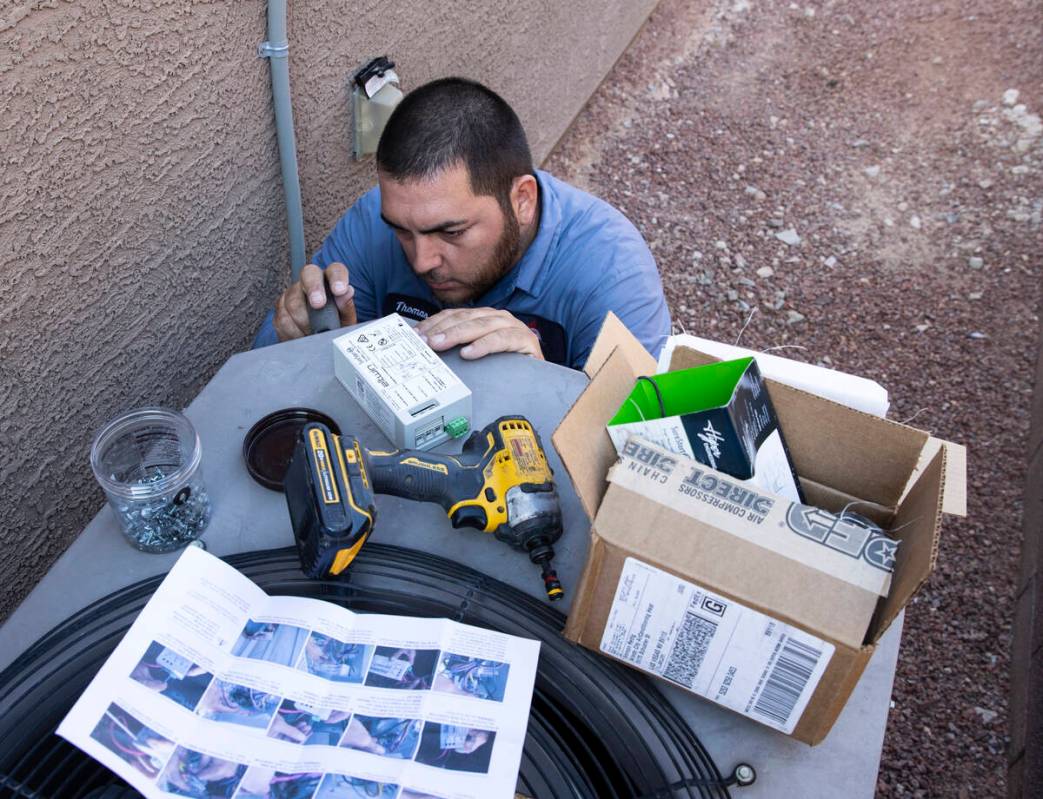 Windy City Air's technician Thomas Padron installs a soft starter as he repairs an air conditio ...