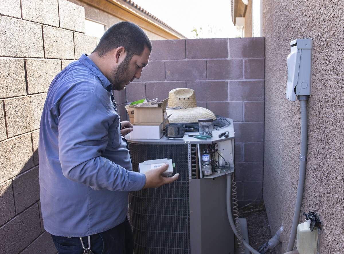 Windy City Air's technician Thomas Padron prepares to install a soft starter as he repairs an a ...